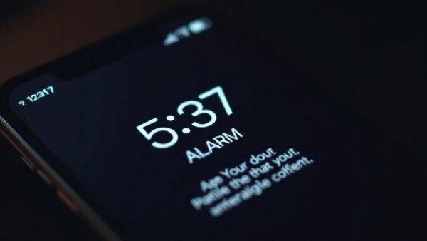 Smartphone alarm with motivational text for waking up early success.