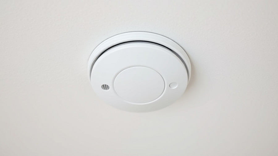 White smoke detector on ceiling, illustrating how to test smoke detectors.