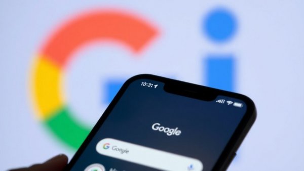 Close-up of Google app on smartphone, AI logo in background.