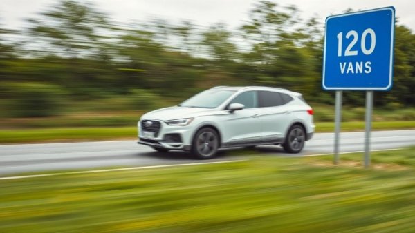 Blurred white car near A20 Bau Bad Segeberg sign, roadside view.