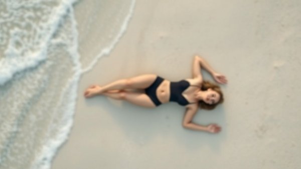 Blurred aerial woman on sandy beach in black swimsuit, relaxed.