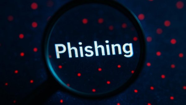 Magnifying glass highlighting phishing threat against a blue digital backdrop.