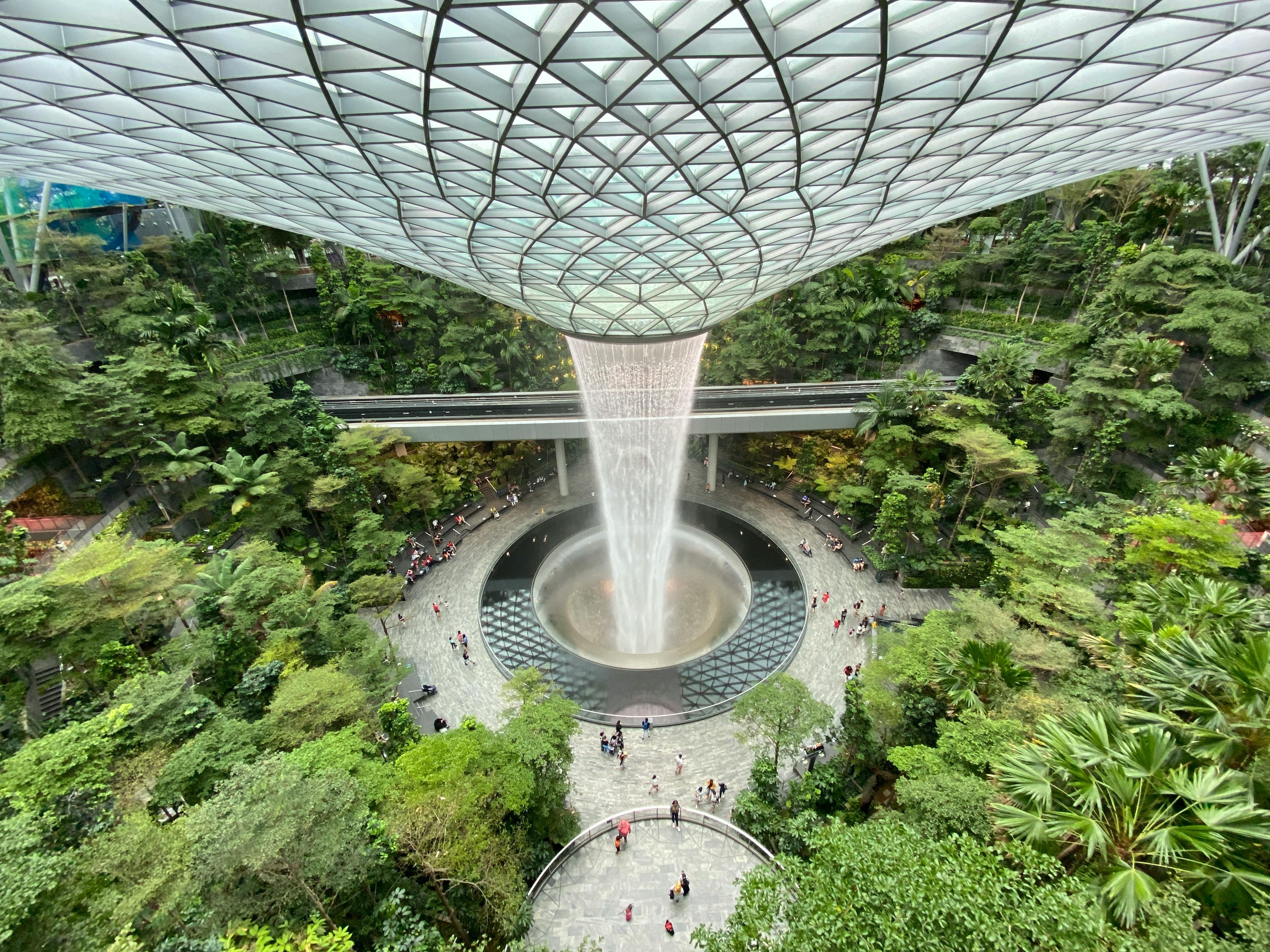 Spectacular indoor waterfall Rain Vortex people marveling cascading water lush garden atrium under massive glass dome