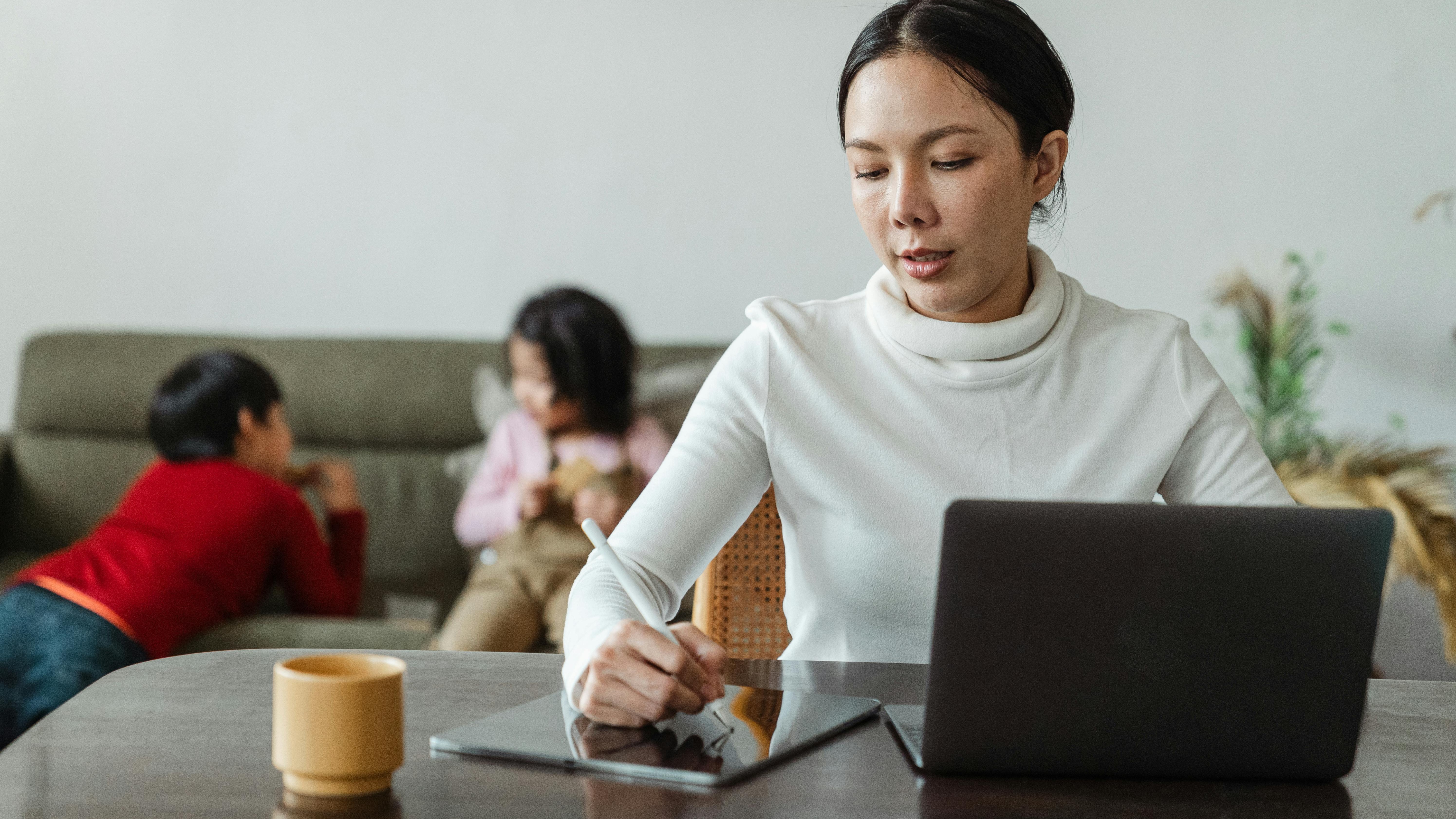 Calm working mom balancing tasks at home with kids.