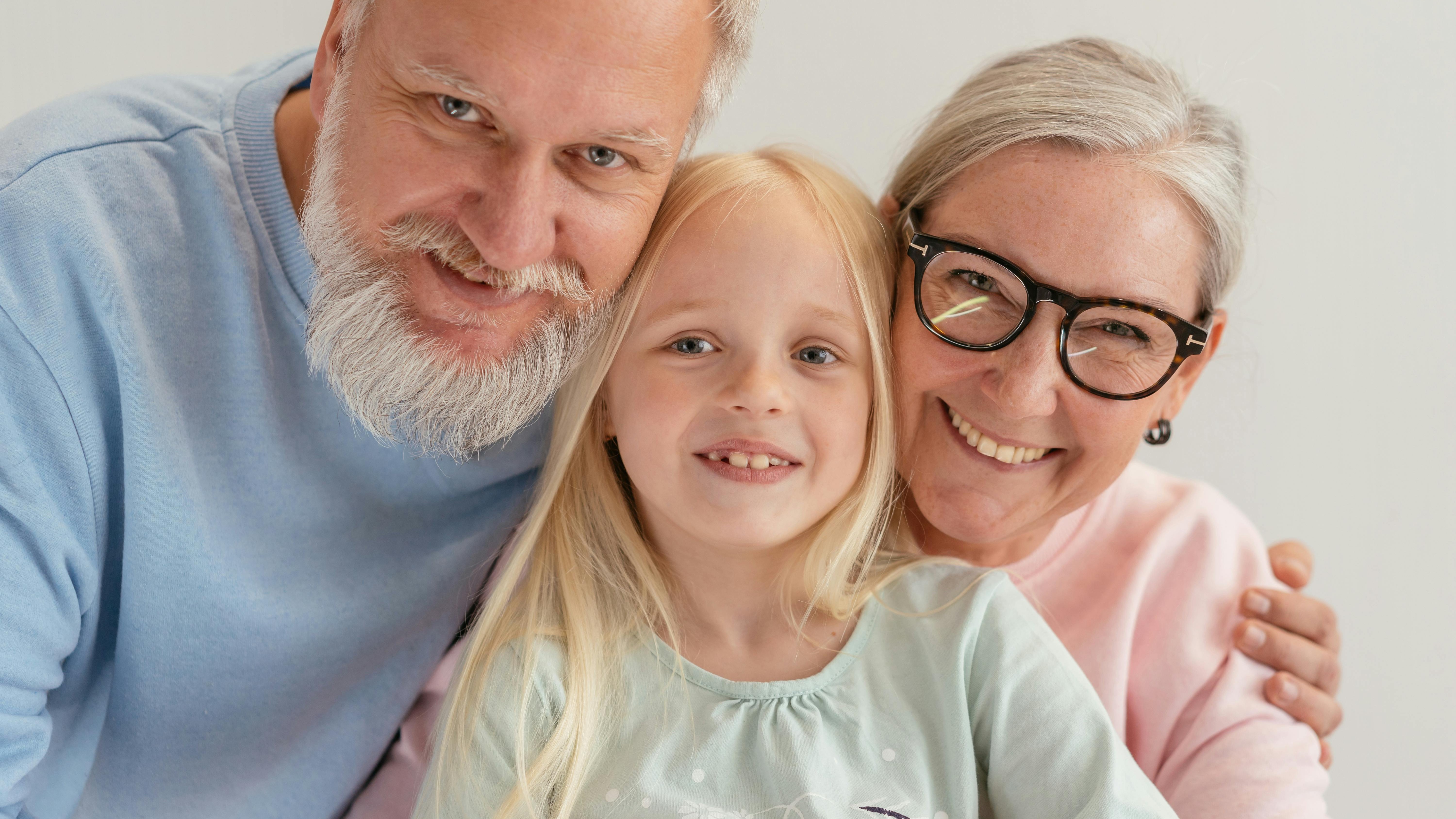 Grandparents helping change baby's diaper in bright room.