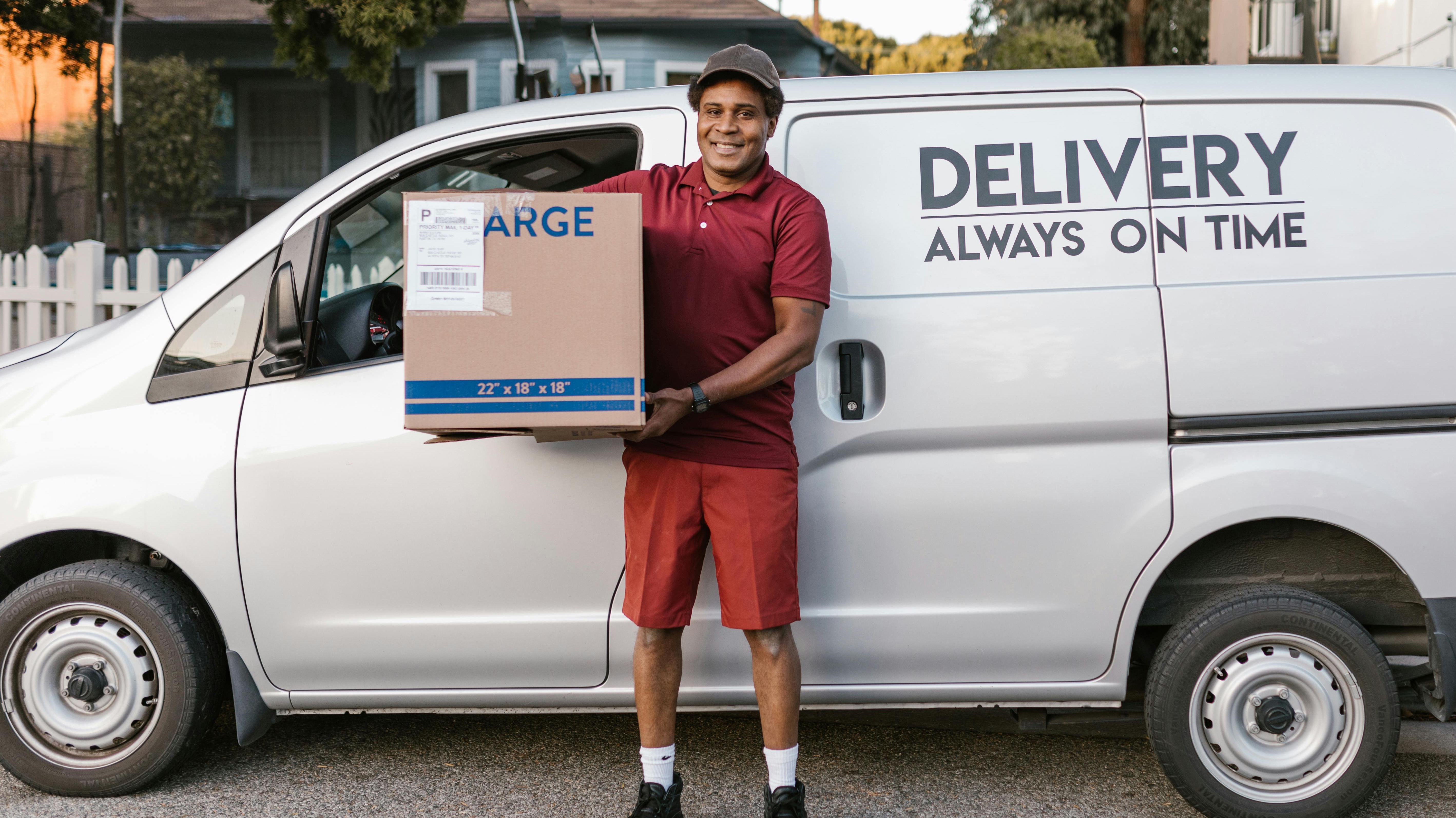 Delivery worker stacking boxes near branded trucks, showcasing hiring trends.