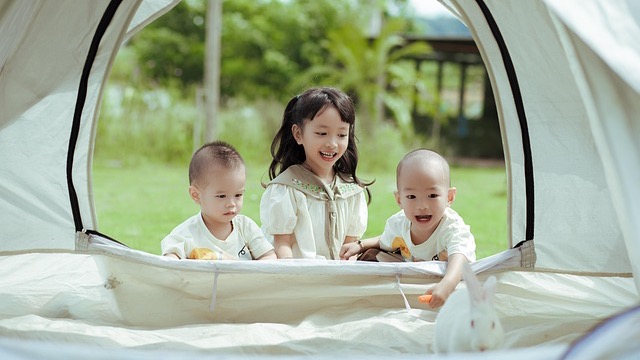 Children enjoying glamping sleepover trend in decorative tent.