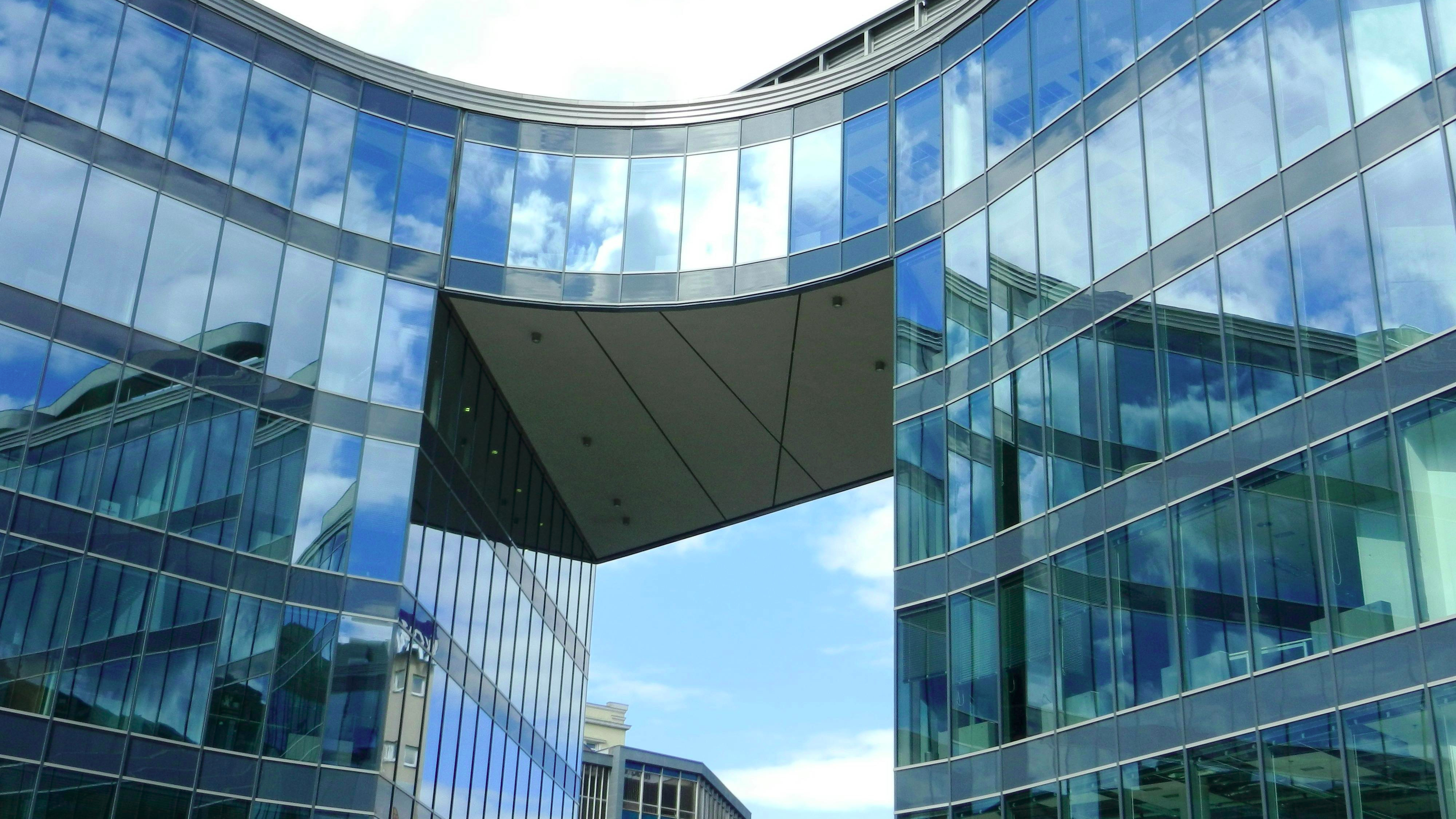Modern medical building reflecting sky, urgent care signage.
