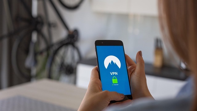 Best VPN for gaming: Woman using laptop with VPN hologram.