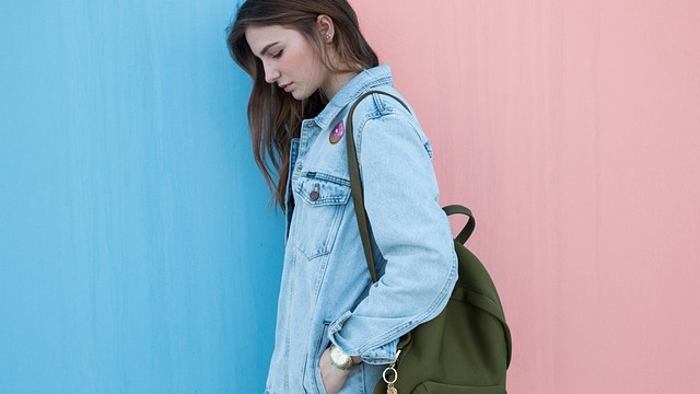 Maternity fashion trends 2026: Elegant white dress on smiling woman, blue backdrop.
