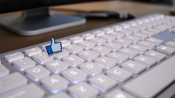 Keyboard with social media like and dislike buttons, symbolizing job hopping and security clearance.