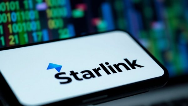 Starlink logo on smartphone with blurred code, symbolizing broadband infrastructure funding.