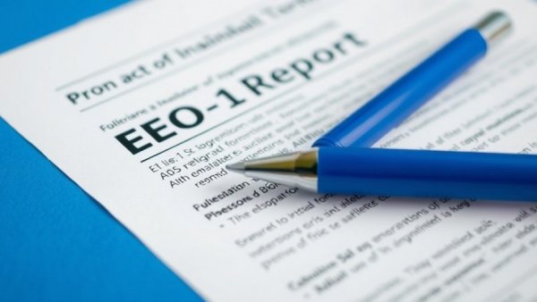 EEO-1 reporting requirements form with pen on blue surface.