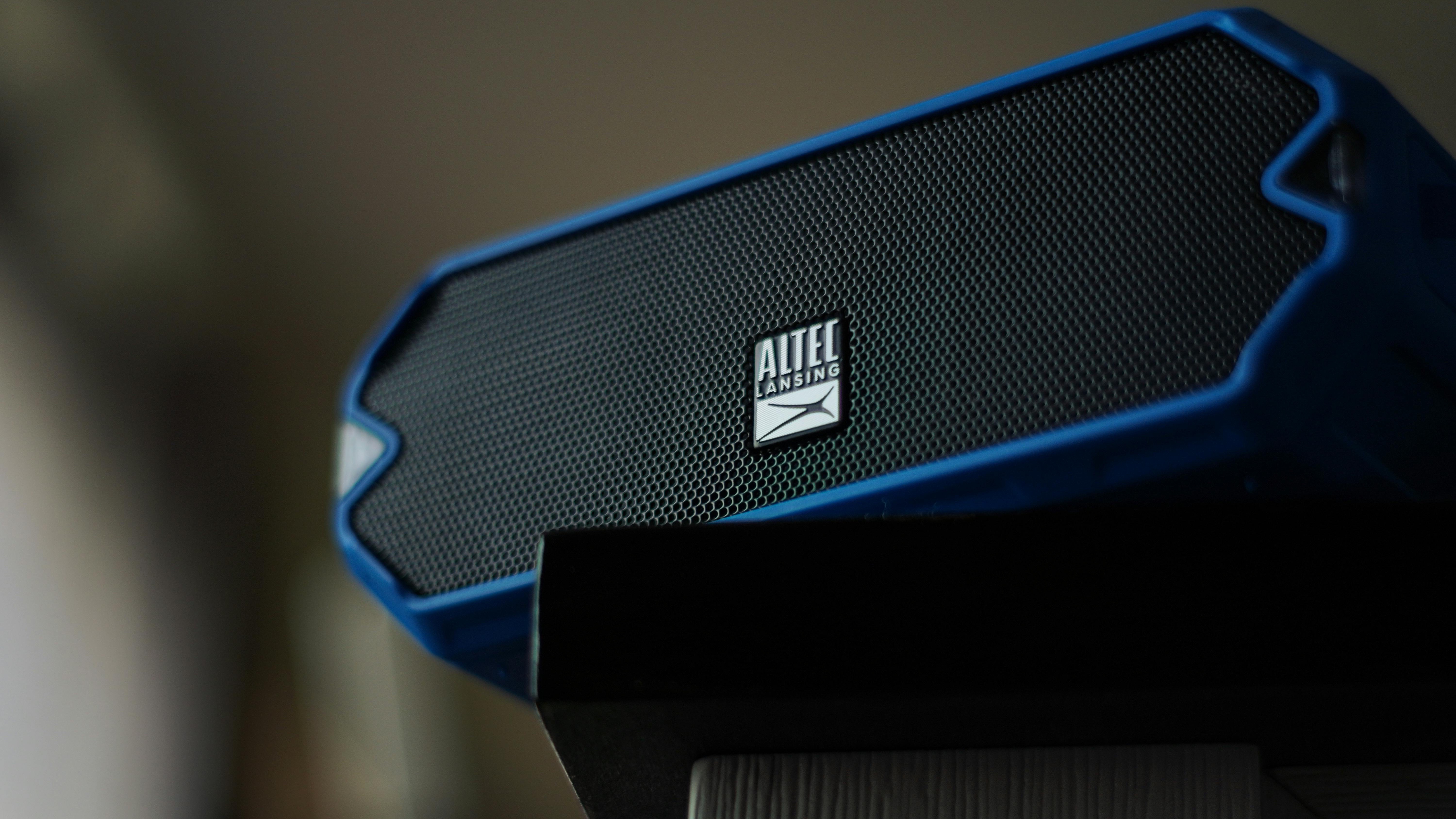 Smart speaker on wooden shelf, person adjusting settings, cozy decor.