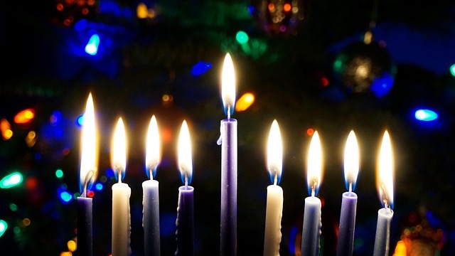 Child observing menorah lighting during Hanukkah dinner.