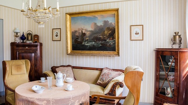 Traditional dining room with outdated features like floral curtains and striped wallpaper, showcasing classic dining elements and soft natural lighting.