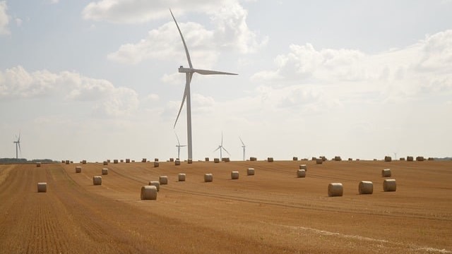 Aerial view of wind turbine over green farmland, related to Australia solar energy and battery storage.