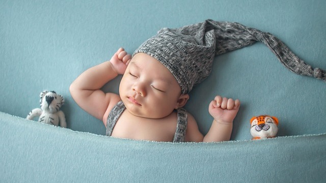 Peaceful child asleep with teddy bear on yellow pillow.