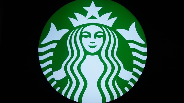 Close-up of Starbucks logo on building exterior related to labor law settlement.