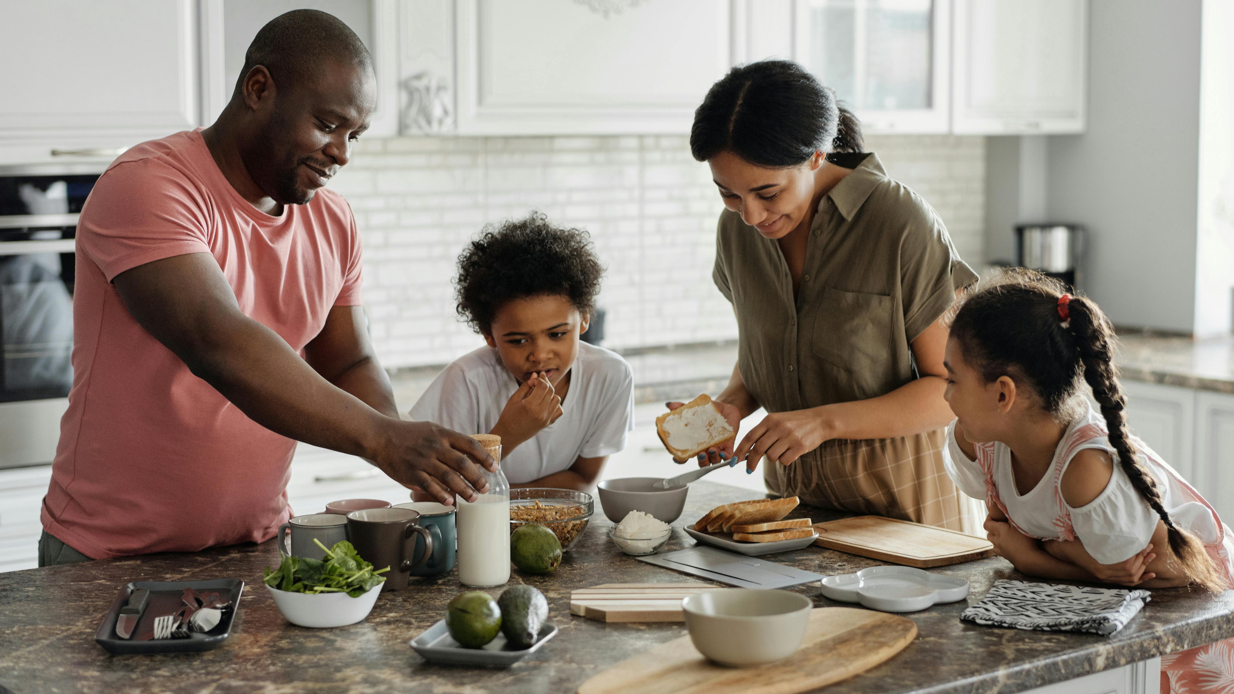 Diverse parents discussing co-parenting strategies at kitchen table.