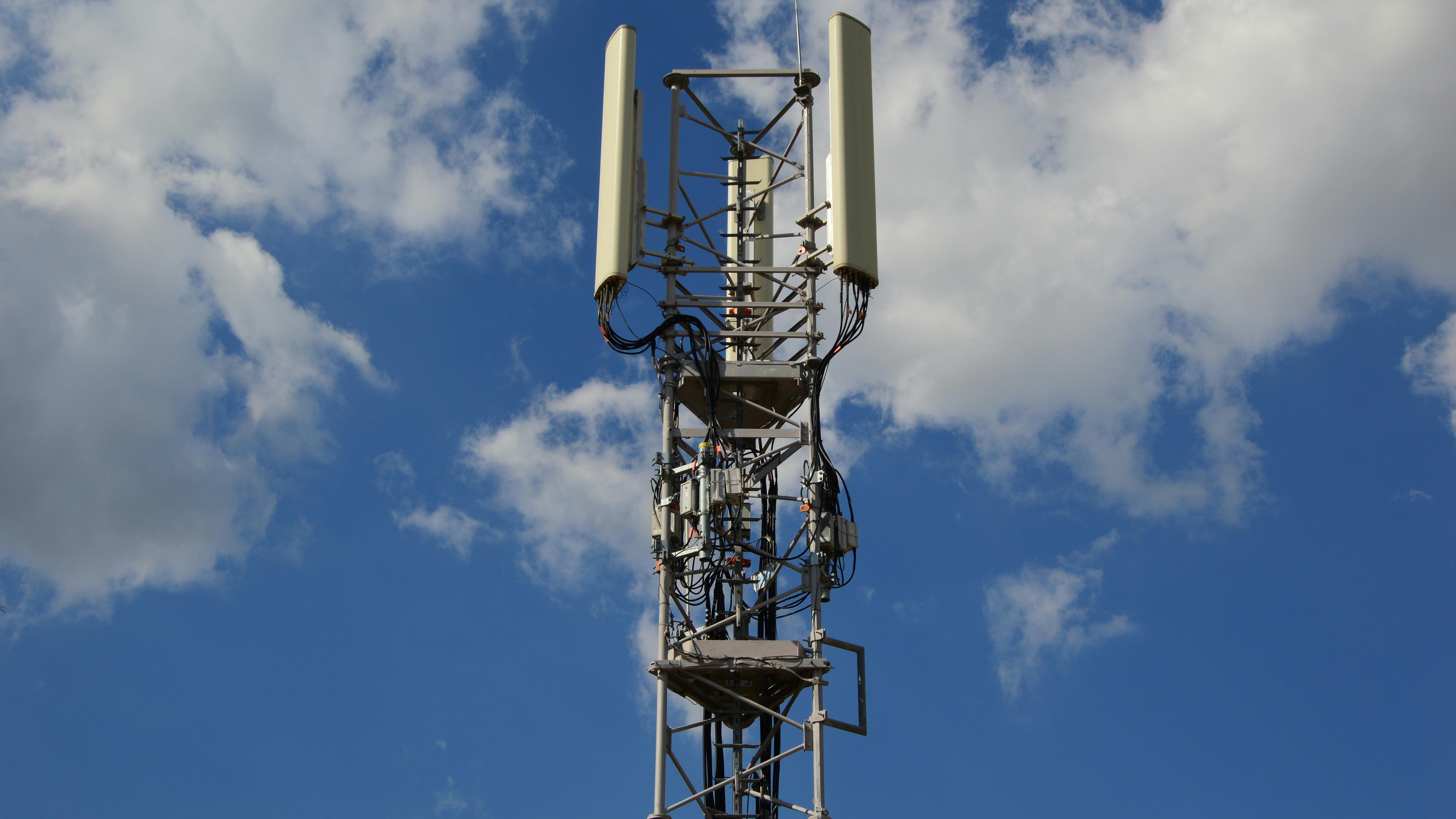 Modern glass building with a group of people outside discussing 5G Market Stability.