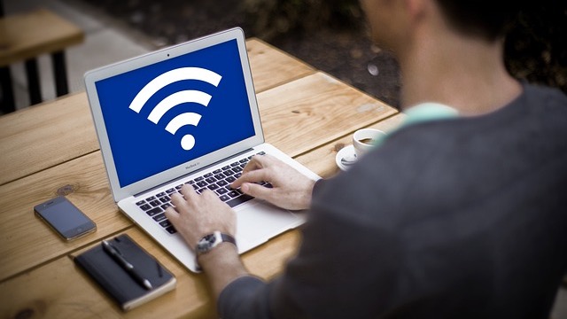 Two women interacting with a device under a Wi-Fi symbol, showing 6 GHz Wi-Fi benefits.