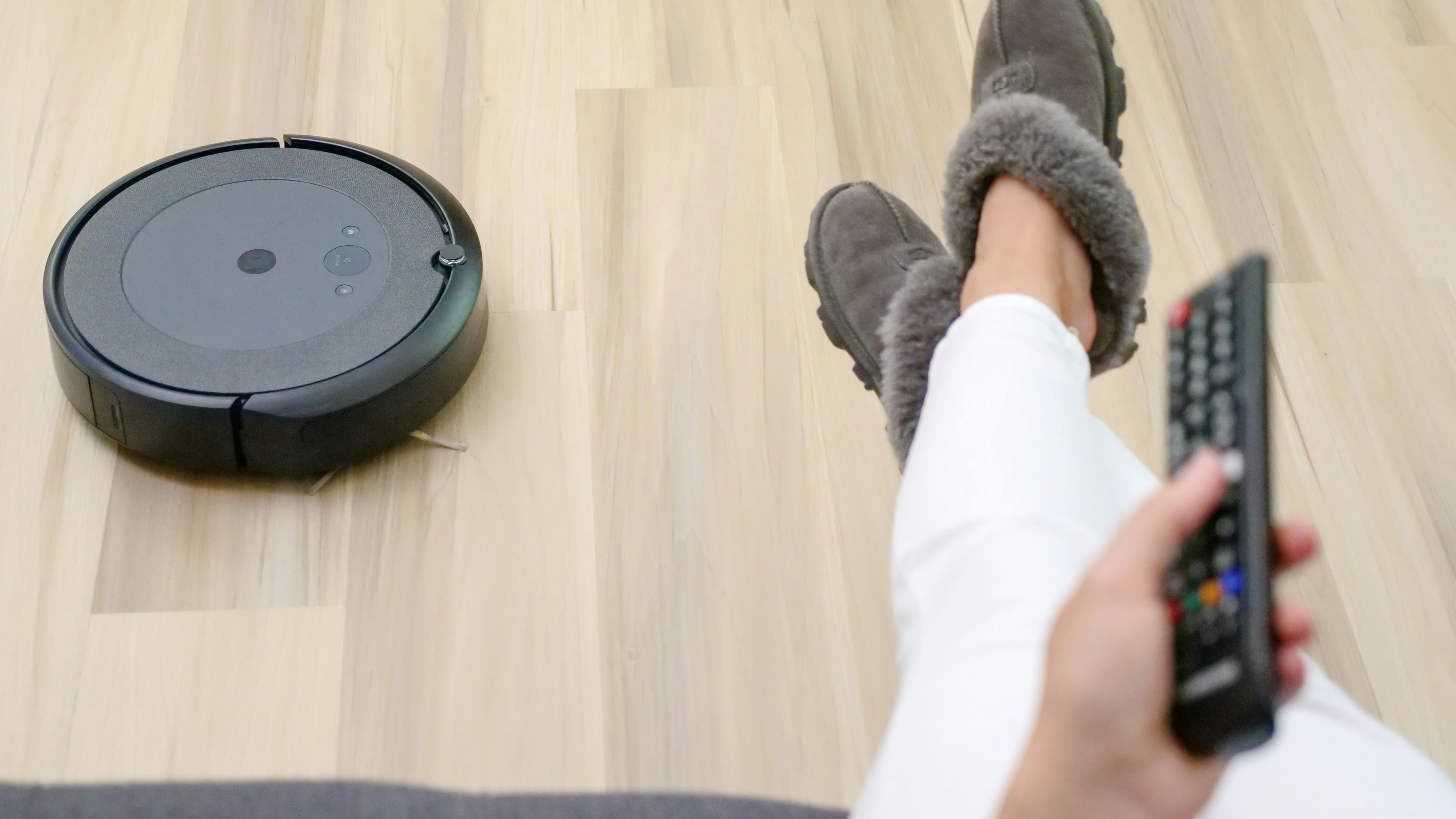 Modern robot vacuum with obstacle avoidance on wooden floor.