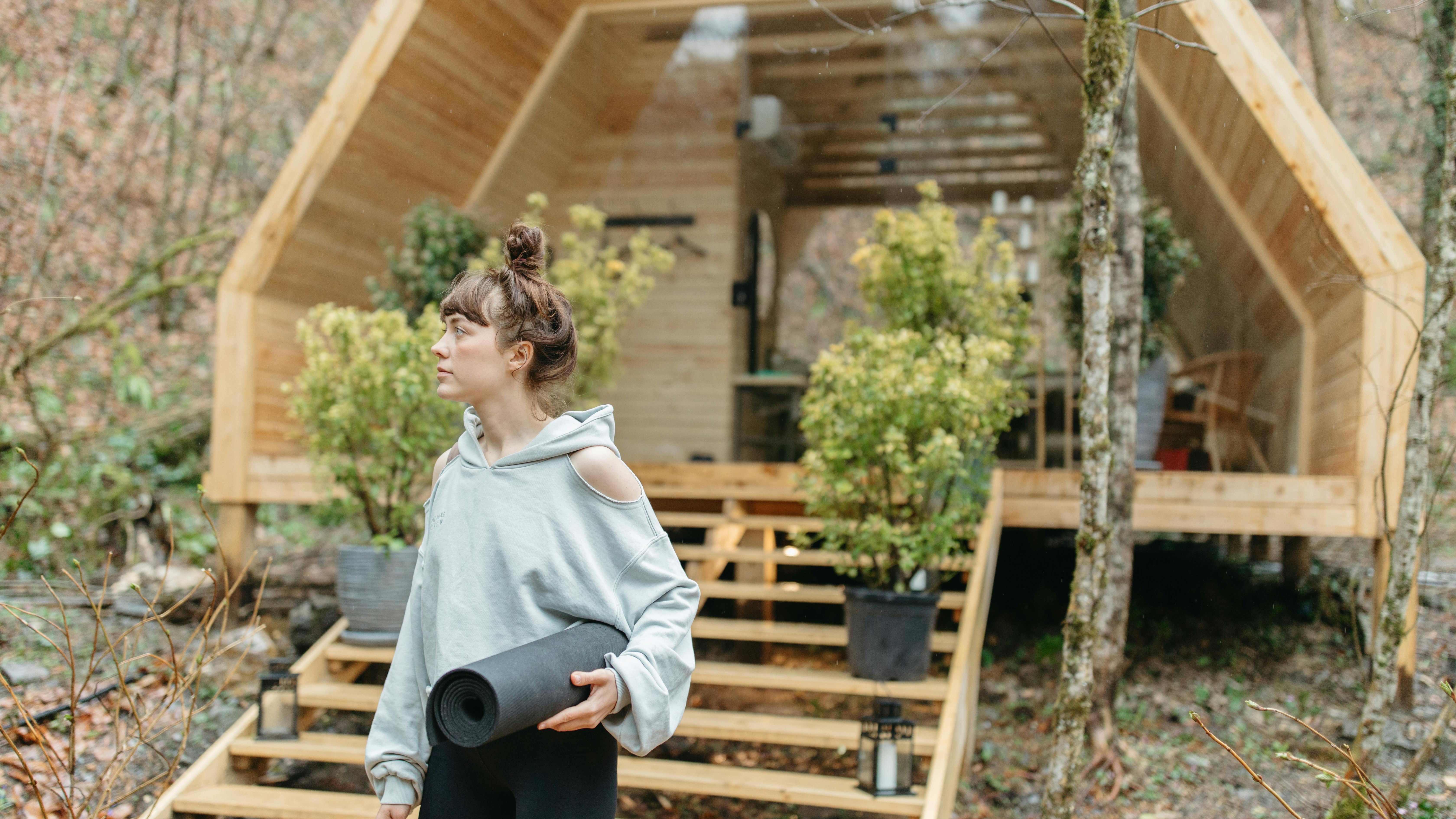 Cheerful woman in front of a green container home in a tropical setting.
