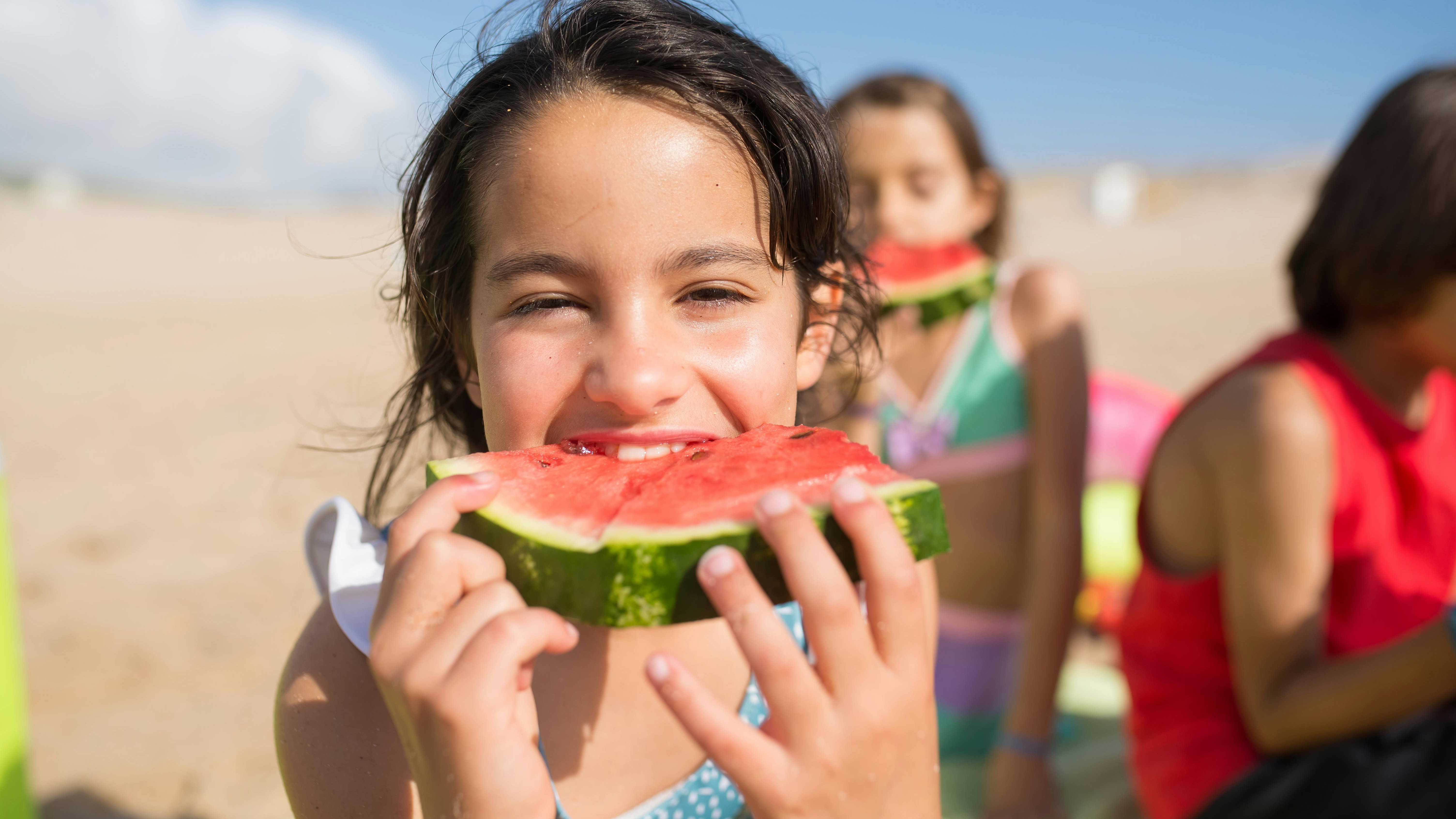 Child holding fruit containers, promoting healthy family meals.