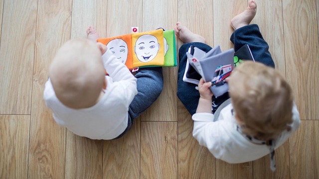 Cartoon toddlers smiling and playing in a sunny garden scene.
