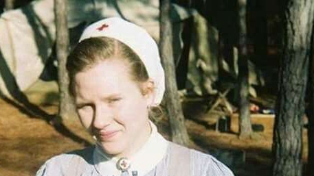 WWII women ambulance driver in uniform with flags, historical.