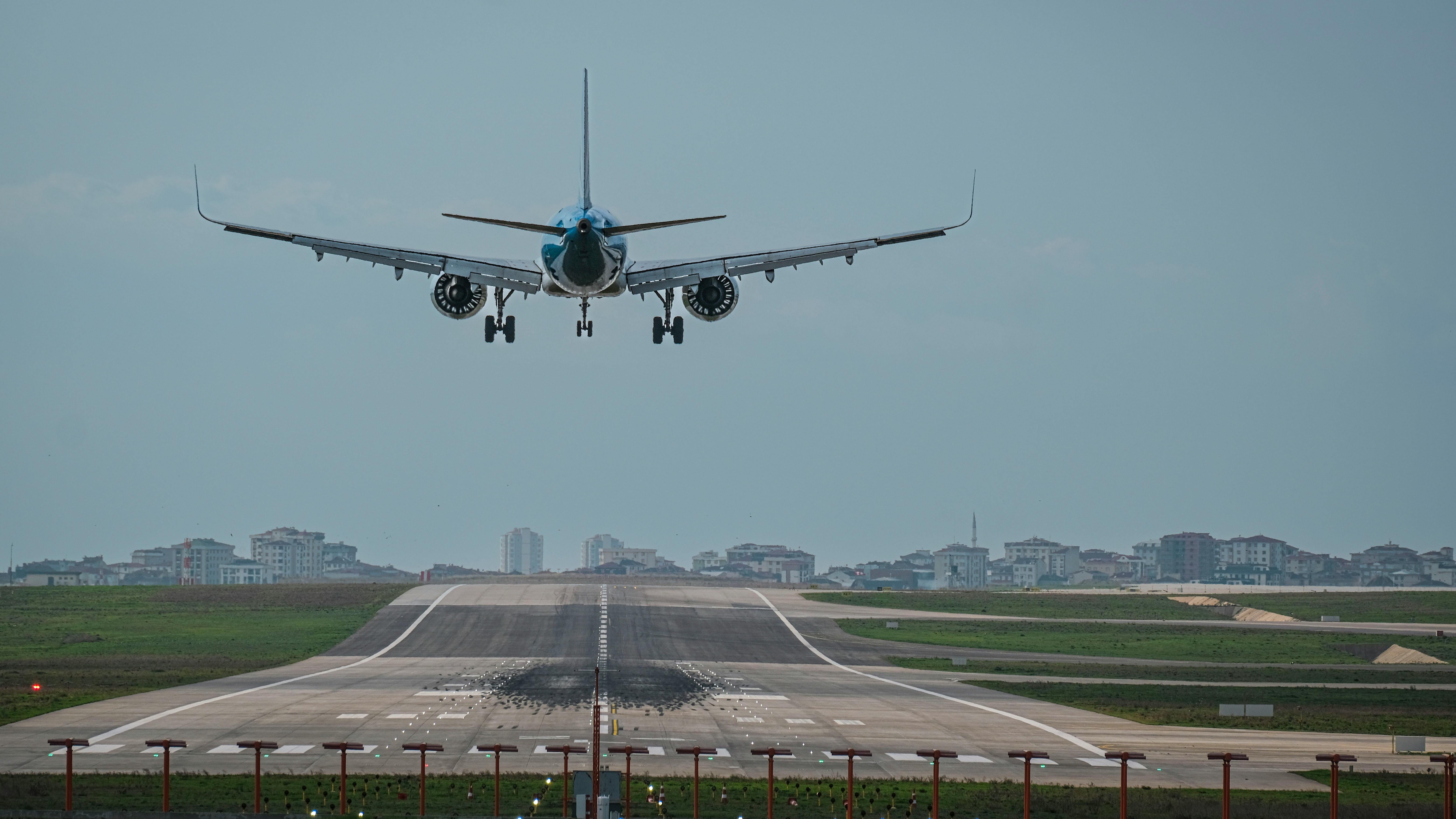 Boeing employees discussing under aircraft tail in industrial hangar.