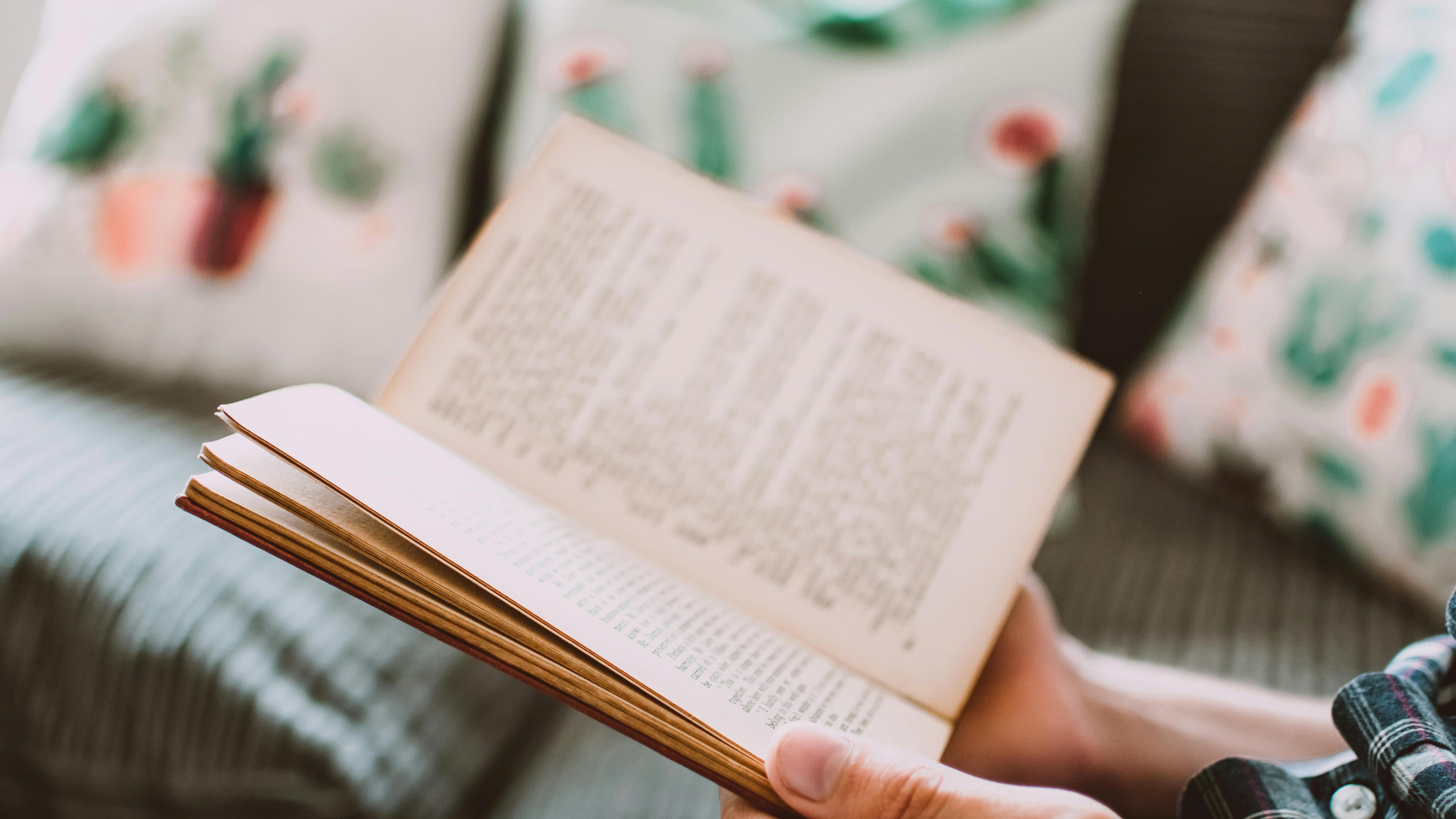 Hands holding a purple book with 'W', Influential Business Women Reading Lists.