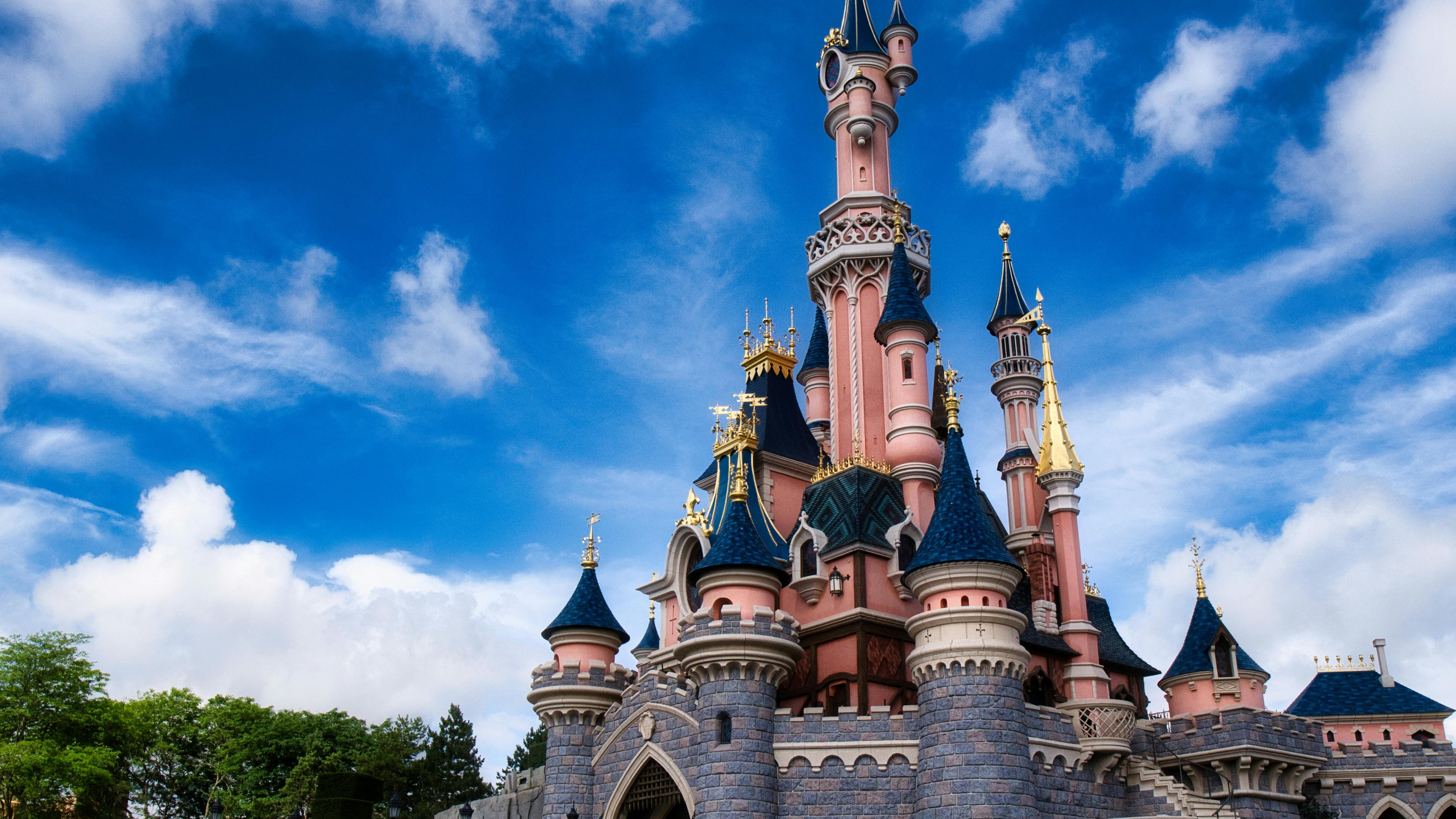 Cheerful character poses in front of a whimsical castle.