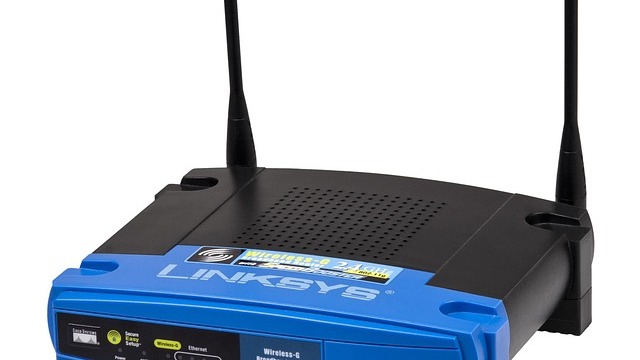 Woman adjusting Wi-Fi router on desk to boost Wi-Fi signal.