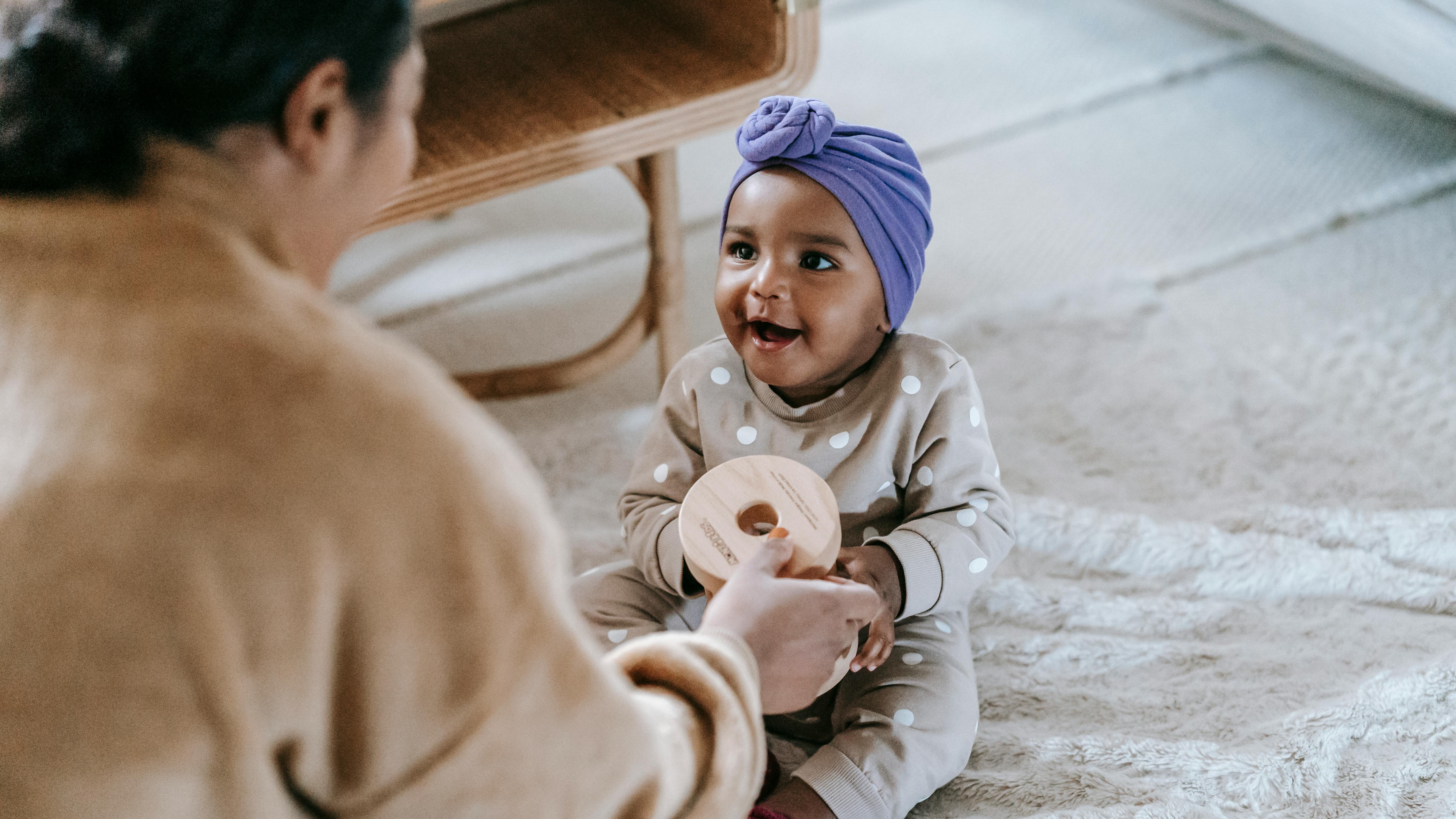 Adorable baby inside a colorful pack and play in bedroom setting, Best Pack and Plays of 2025.