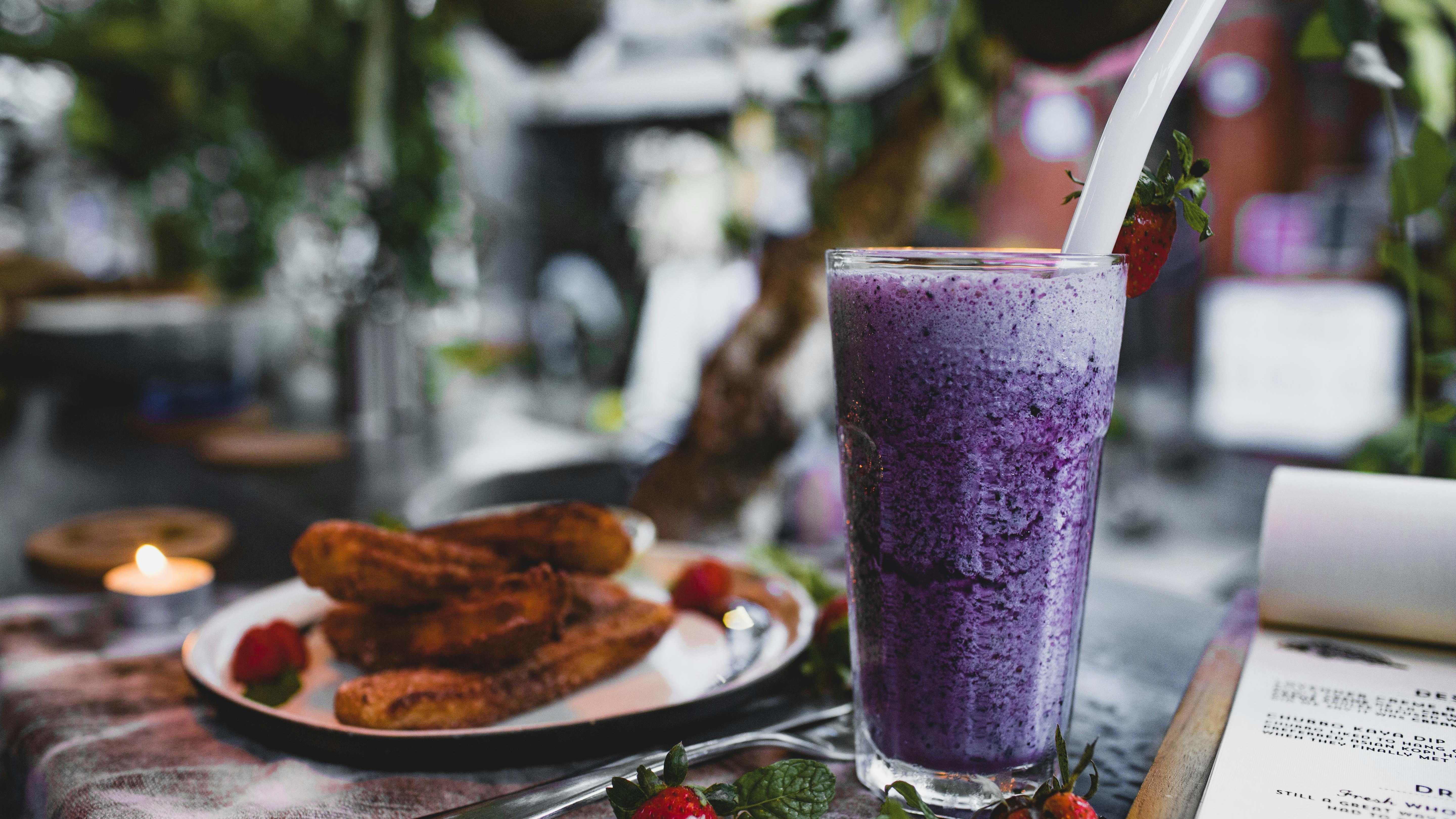 Blueberry smoothie with milk in colorful cups, marble countertop.