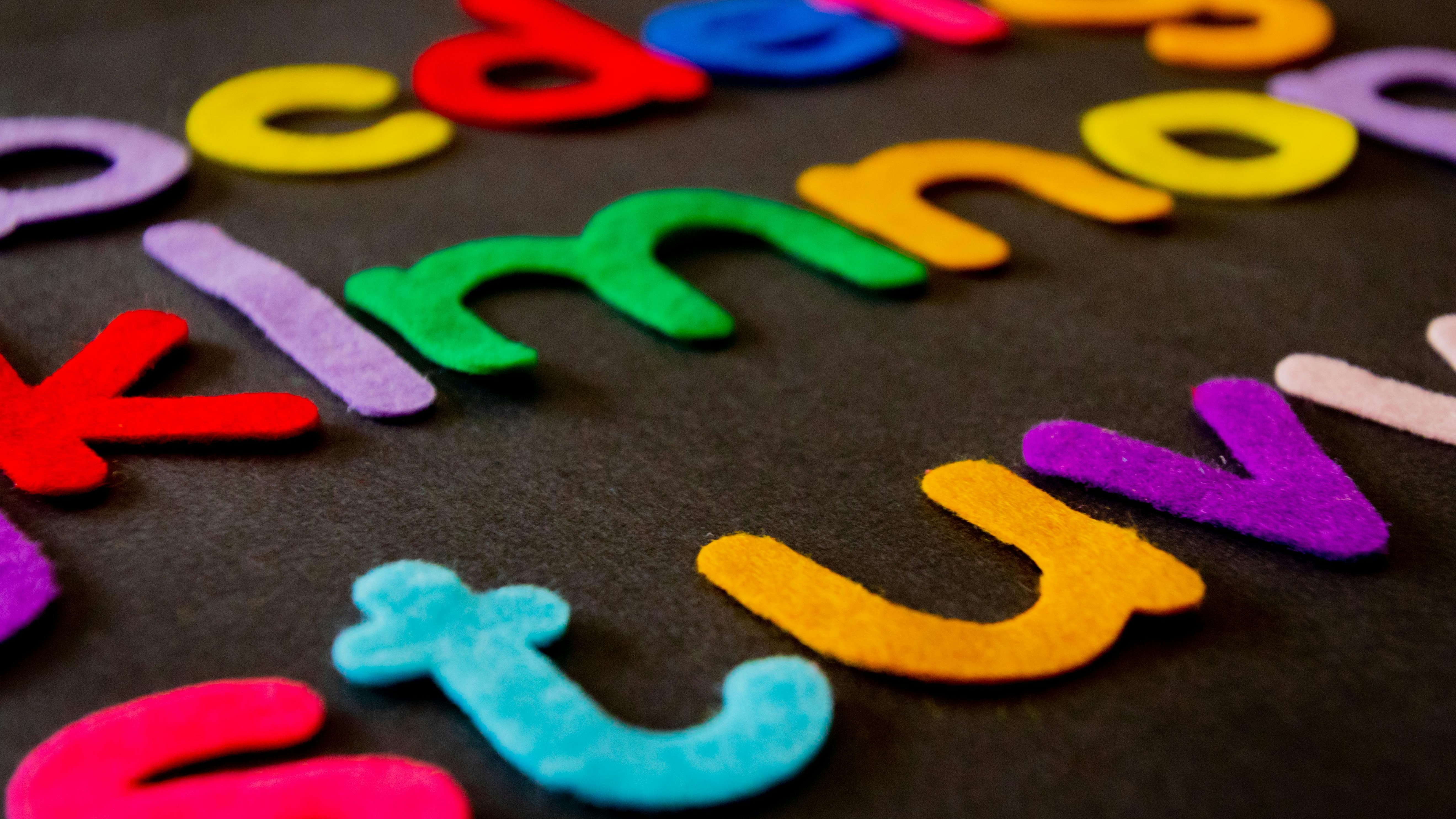 Child organizing colorful alphabet pieces on a wall, early learning activity.