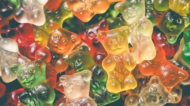 Close-up of hands holding gummy vitamins for kids on marble.