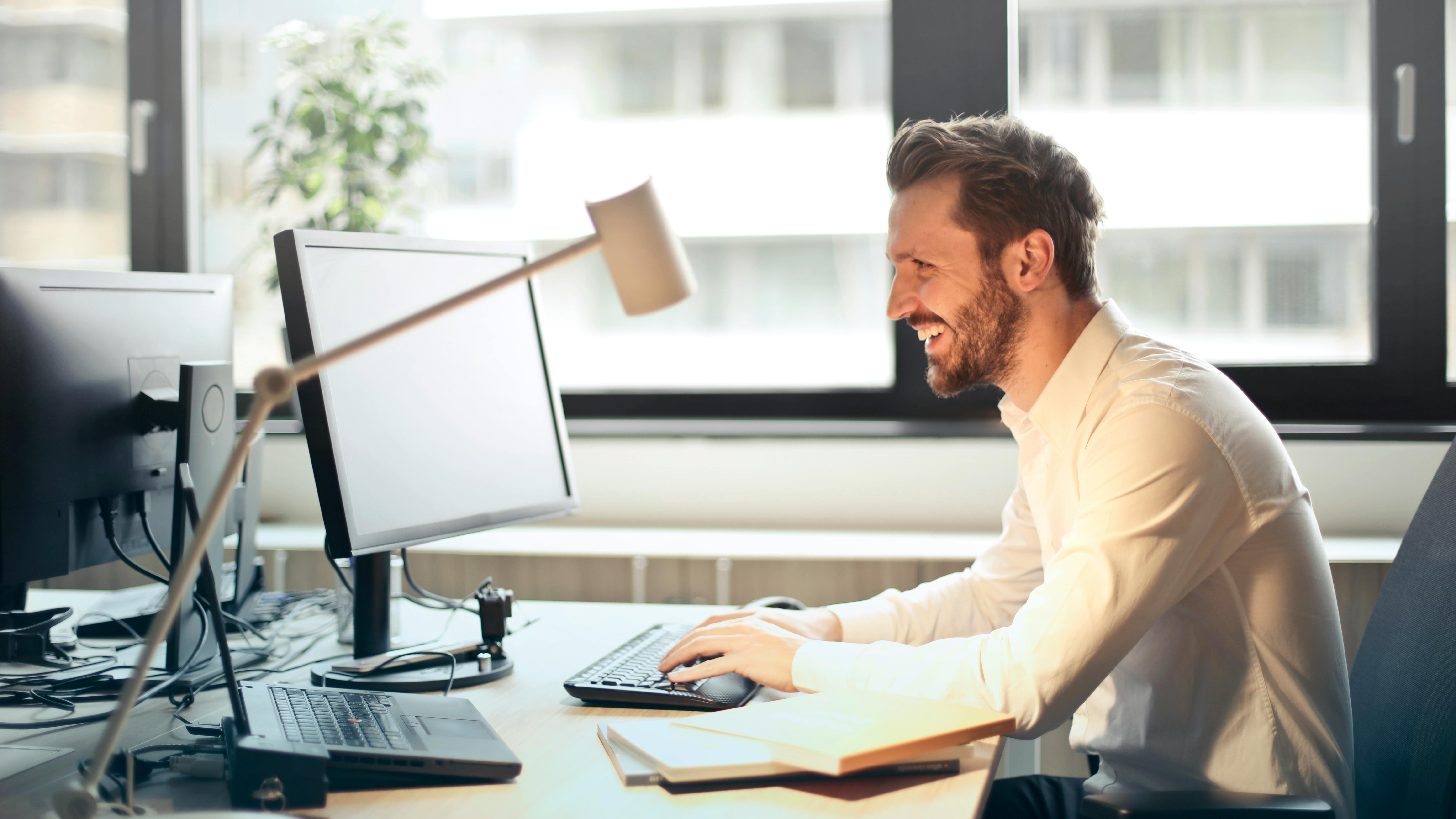 Tech professional silhouette working at a multi-screen setup.