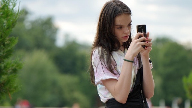 Teenage communication; girl relaxing with book on face in garden.