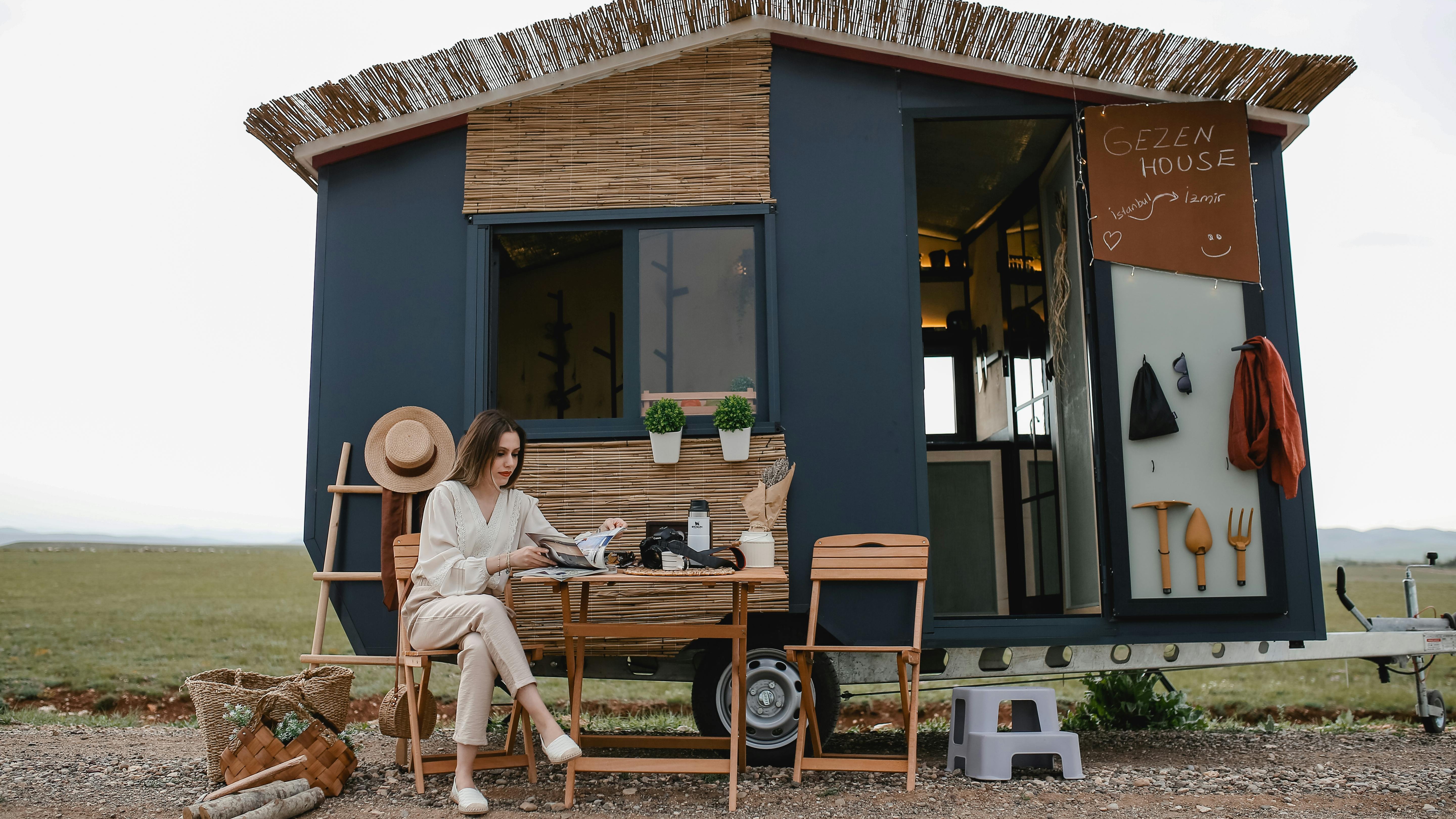 Used tiny house in a field with blue sky and clouds.