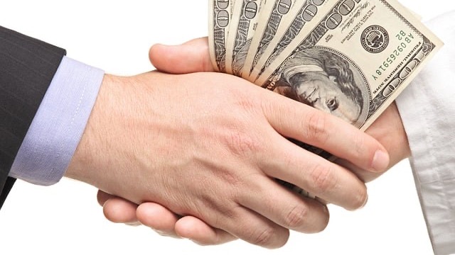 Close-up of hands exchanging cash - how much to tip movers discussion.