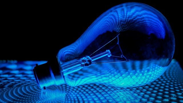 Futuristic smart lighting bulb with pink glow on terrazzo base.