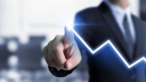 Future of work automation represented by a hand pointing at financial graphs on a screen.