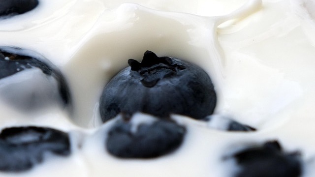 Three jars of healthy blueberry yogurt on a countertop.