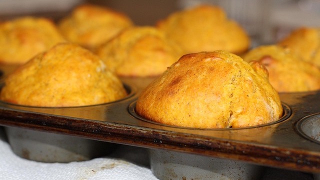 Lemon poppyseed muffins on marble with lemon halves.