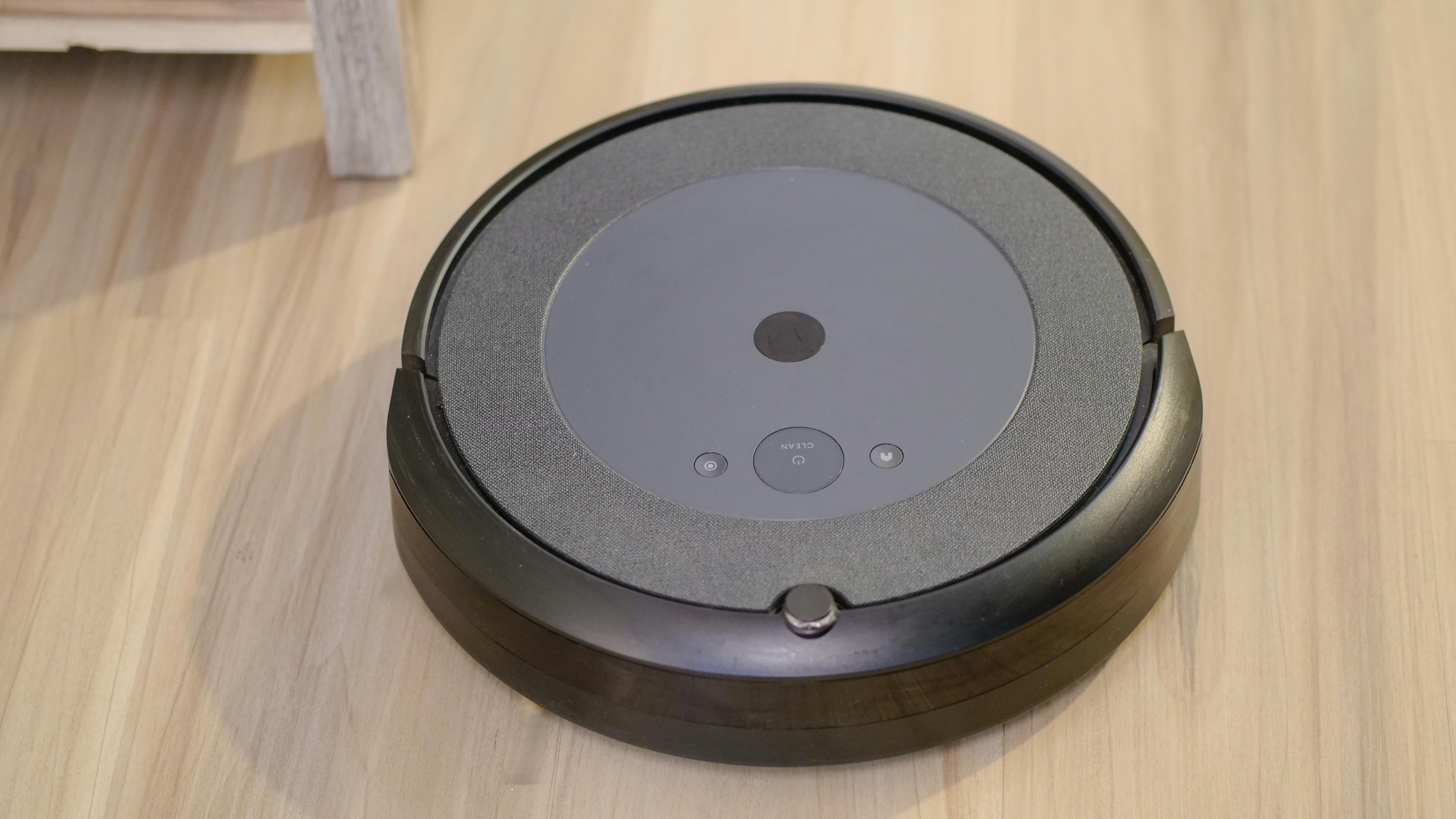 Modern white robot vacuum cleaning carpet next to a couch, optimal connectivity.