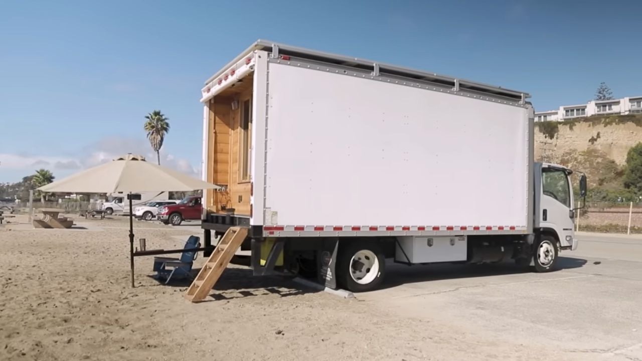 Off-grid tiny living setup in a converted truck on a beach.