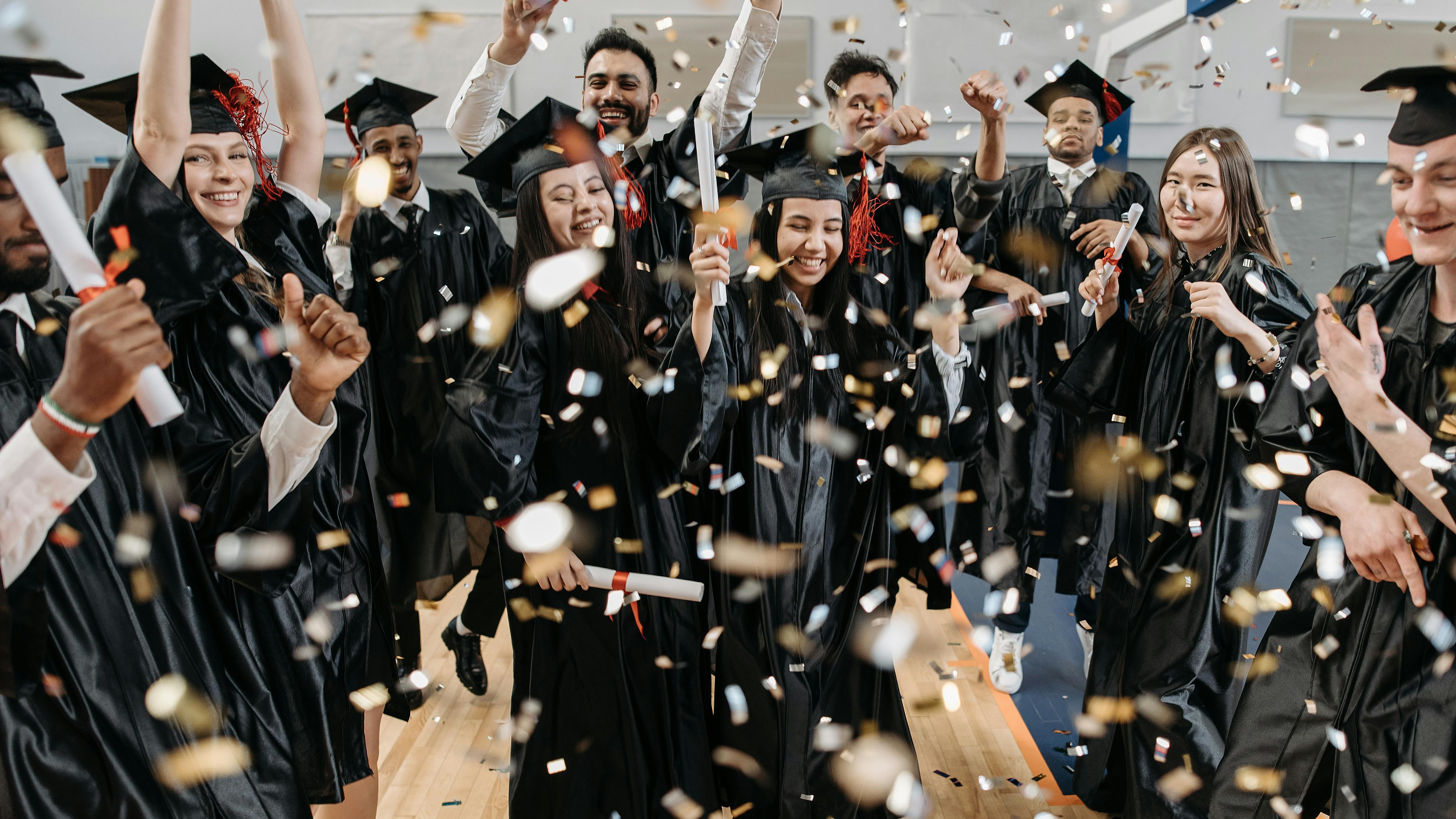 Graduates with caps and orange tassels at a ceremony, Class of 2025.